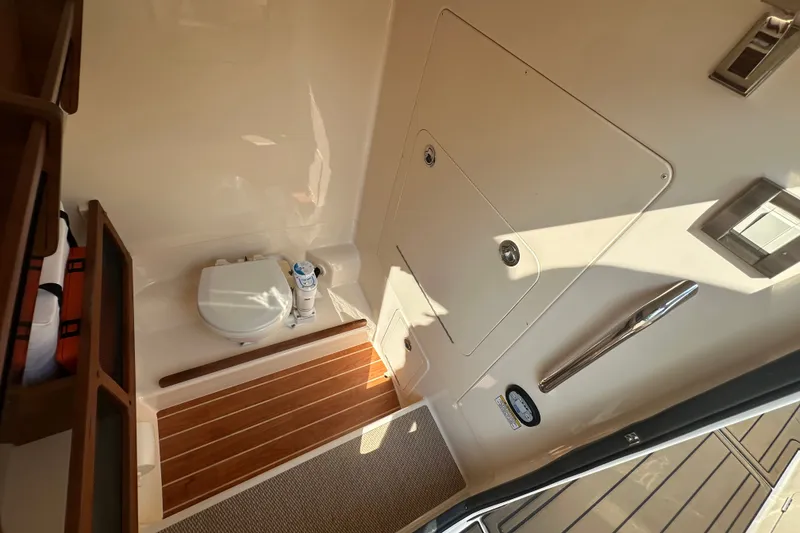 Slide: The Image of 2023 Grady-White 281 Coastal Explorer boat interior with compact toilet and wooden flooring. - 28