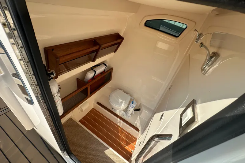 Slide: The Image of 2023 Grady-White 281 Coastal Explorer boat interior with toilet and wooden shelves. - 29