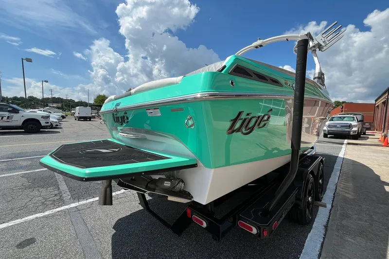 Slide: The Image of 2020 Tigé 23ZX boat on trailer, vibrant teal color, parked under a cloudy sky. - 6