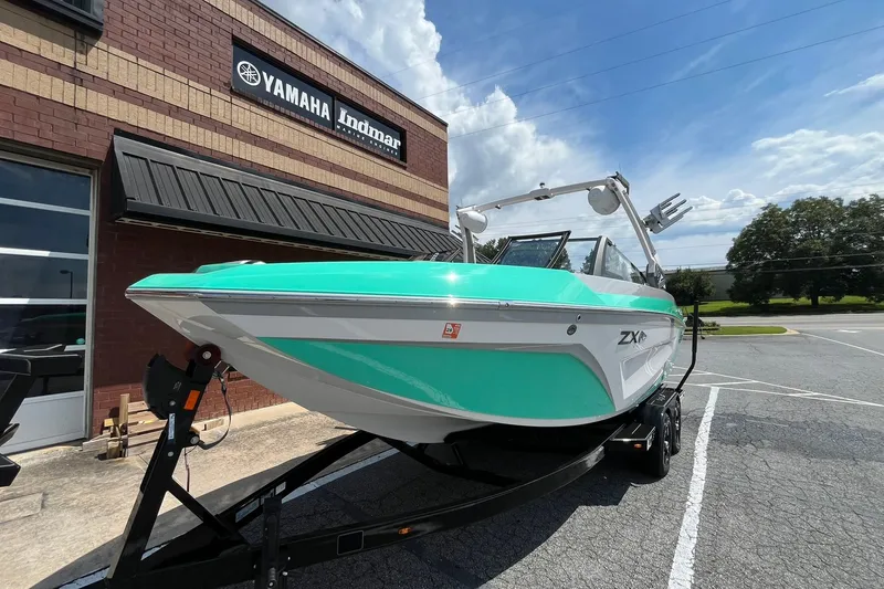 Slide: The Image of 2020 Tigé 23ZX boat in vibrant turquoise, parked outside Yamaha Indmar dealership. - 4