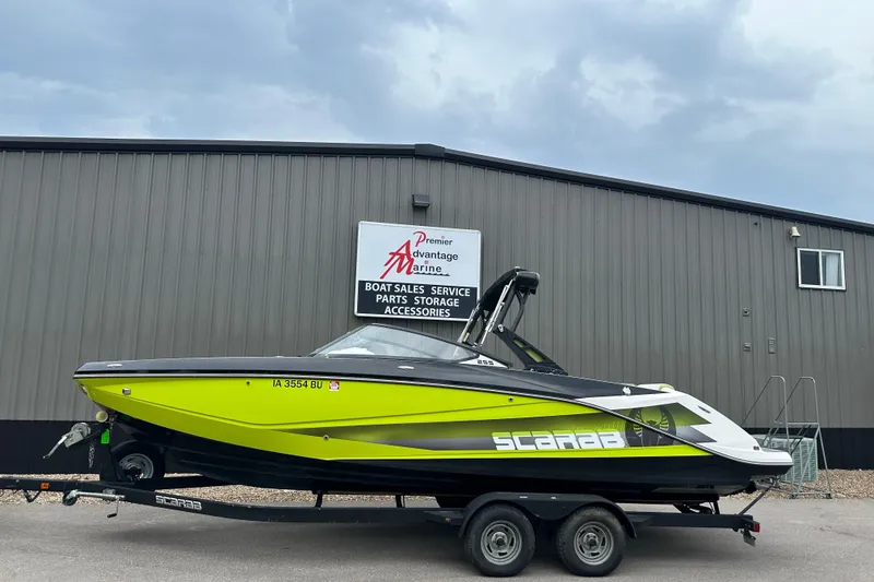 The Image of 2017 Scarab 255 boat in vibrant green on trailer outside marine shop. - 1