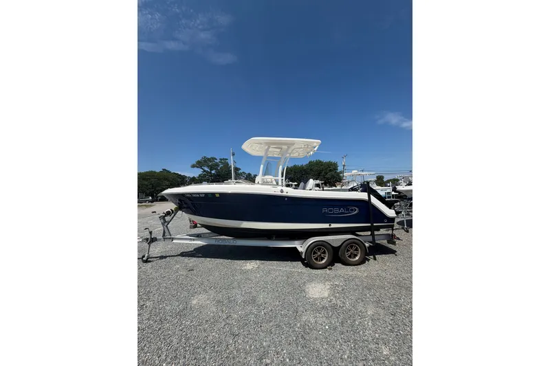 The Image of 2021 Robalo R222 Center Console boat on trailer under clear blue sky. - 0