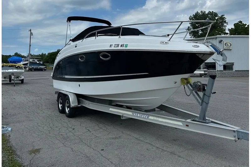 The Image of A 2010 Chaparral Signature 270 on a trailer, featuring a black and white hull, parked in a lot. - 1