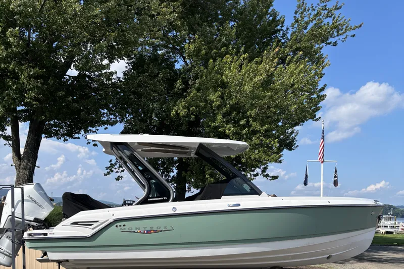 Slide: The Image of 2027 Monterey Elite 25 OB boat docked under trees with clear blue sky. - 2