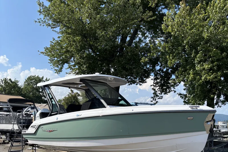 Slide: The Image of 2027 Monterey Elite 25 OB boat displayed outdoors, surrounded by trees and clear sky. - 1