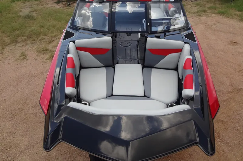 Slide: The Image of 2020 Axis A22 boat interior with red and gray seating, parked on sandy ground. - 8