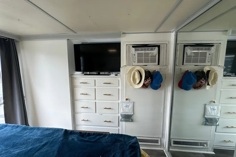Slide: The Image of Interior of a 1980 Lazy Days 14x60, featuring a TV, dresser, and mirrored closet. - 14