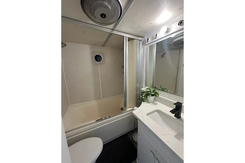 Slide: The Image of Compact 1980 Lazy Days bathroom with bathtub, sink, and porthole window. - 15