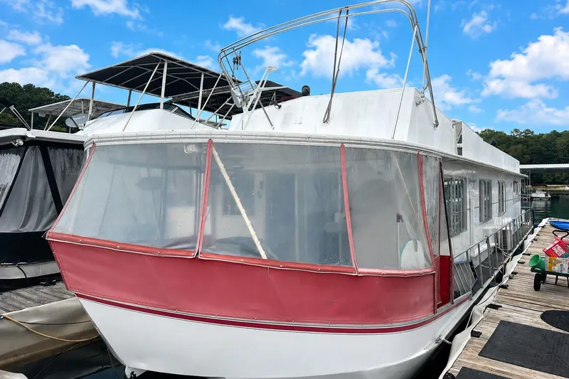 The Image of 1980 Lazy Days 14x60 houseboat docked, featuring red trim and spacious deck area. - 0