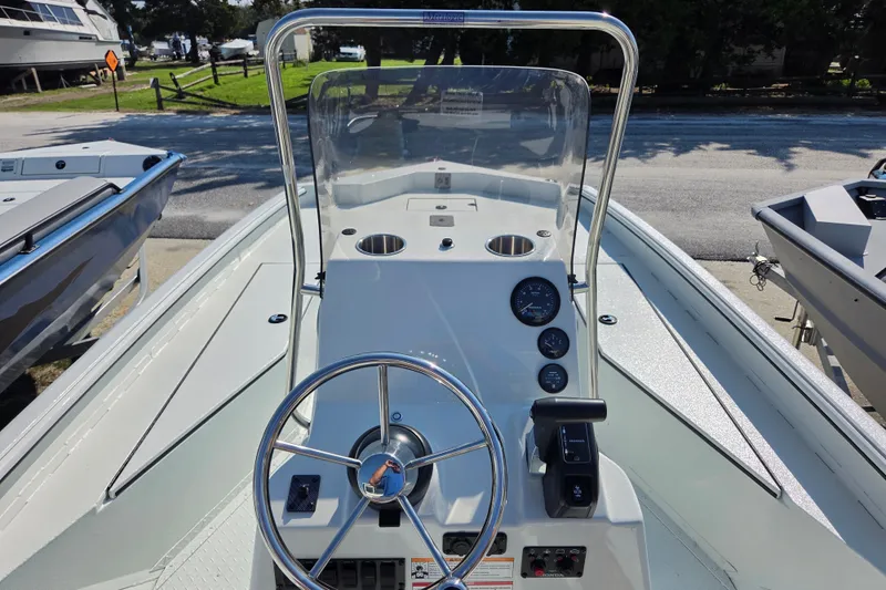 Slide: The Image of 2026 SeaArk Bay Runner 210 boat dashboard with steering wheel and gauges, docked outdoors. - 13
