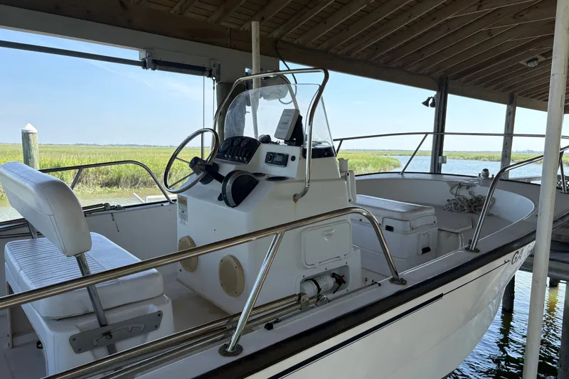 The Image of 2014 Boston Whaler 170 Montauk boat docked under a wooden shelter. - 0