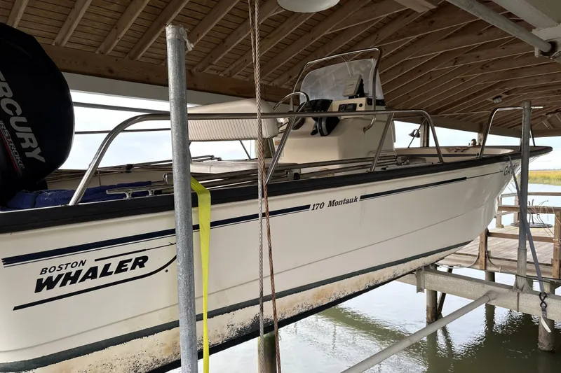 The Image of 2016 Boston Whaler 170 Montauk boat docked under a wooden shelter. - 3