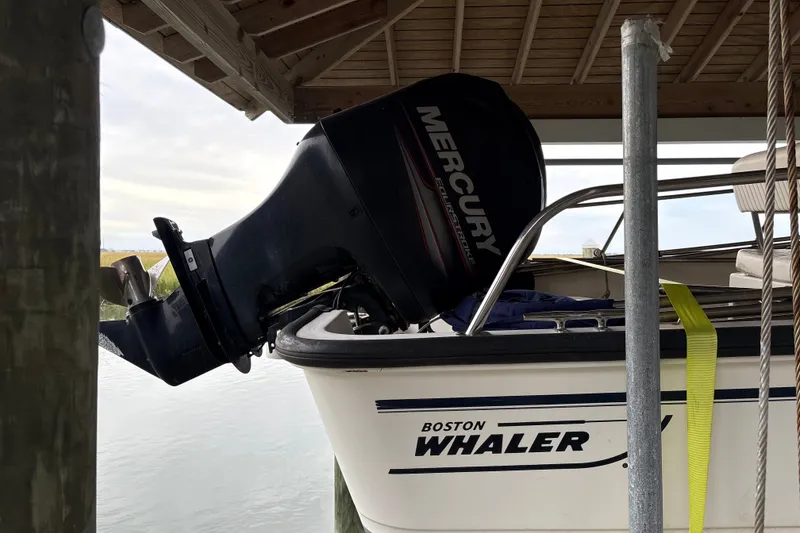 Slide: The Image of 2016 Boston Whaler 170 Montauk with Mercury outboard motor under a dock. - 2