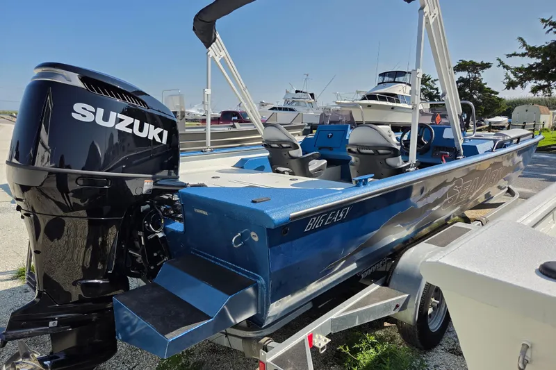 Slide: The Image of 2026 SeaArk Big Easy boat with Suzuki engine, parked on a trailer under clear skies. - 6