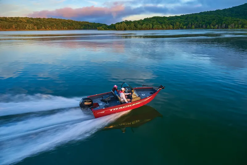 Slide: The Image of Manufacturer Provided Image: 2025 Tracker Pro Guide V-16 WT boat speeding on a serene lake with lush forest backdrop. - 53