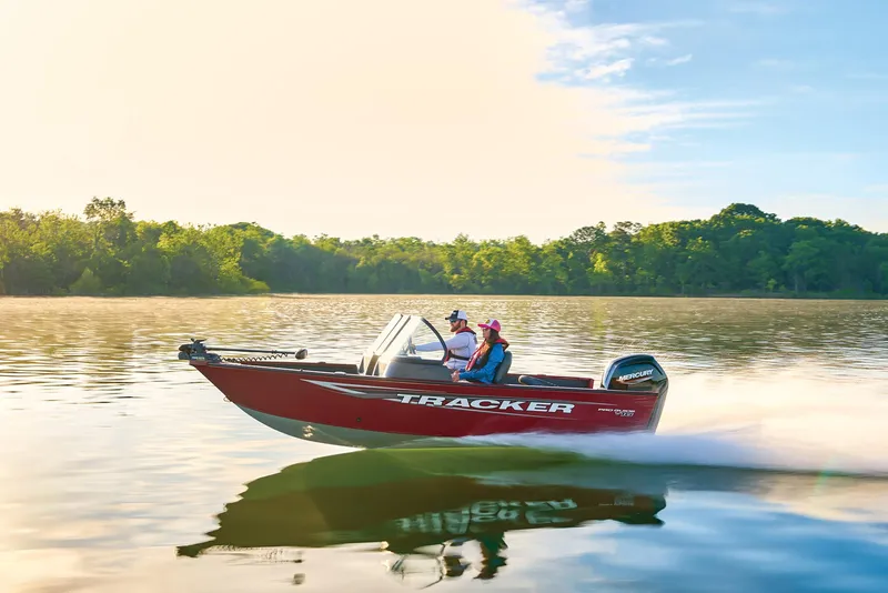 Slide: The Image of Manufacturer Provided Image: 2025 Tracker Pro Guide V-16 WT boat cruising on a serene lake under a clear sky. - 58