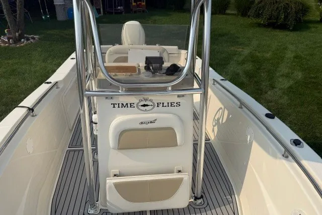 Slide: The Image of 2021 Bulls Bay 230 Center Console boat with "Time Flies" decal, docked on grass. - 22
