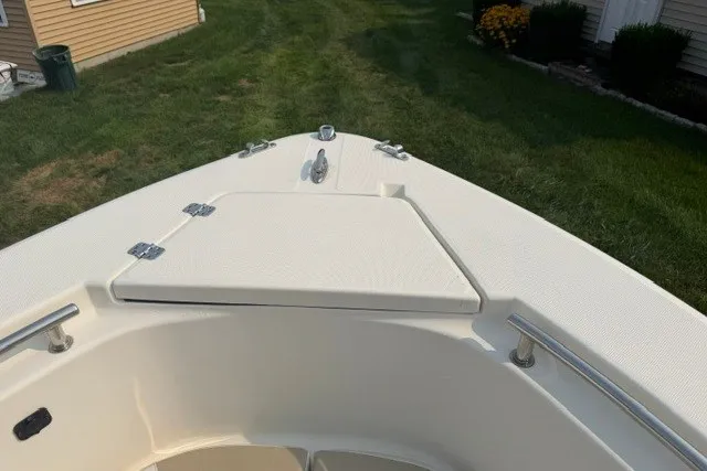 Slide: The Image of 2021 Bulls Bay 230 Center Console boat bow with storage compartment, set on grassy background. - 19