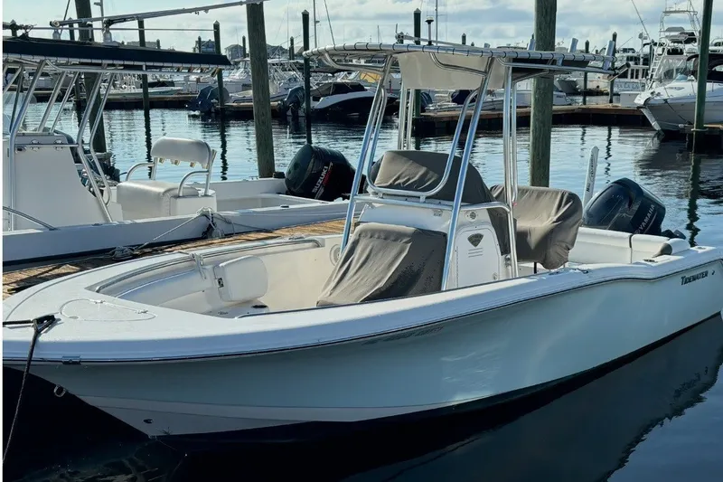 The Image of A white 2015 Tidewater 210 LXF boat is docked in a calm marina. - 0