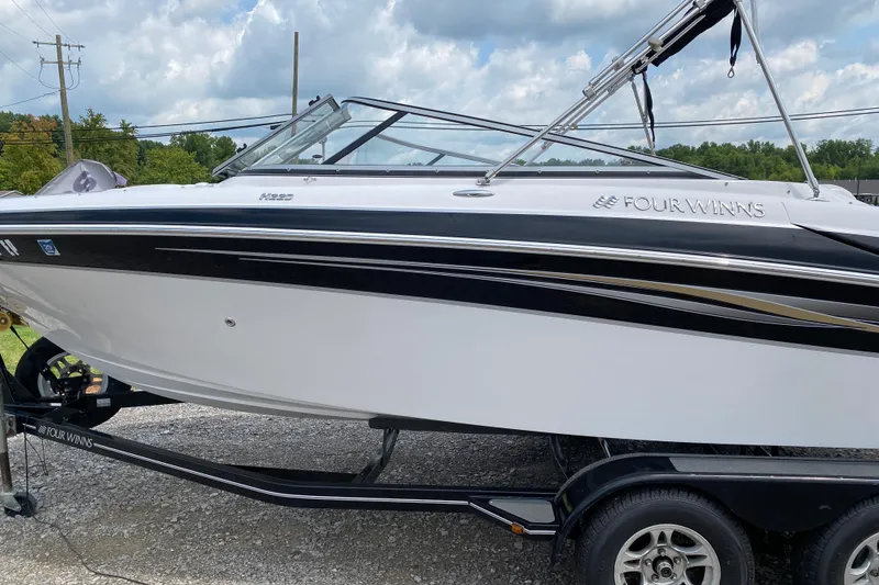 Slide: The Image of 2008 Four Winns H220 boat on trailer, featuring sleek black and white design. - 62