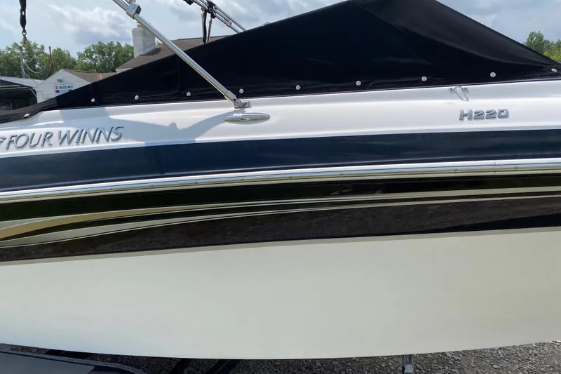 Slide: The Image of 2008 Four Winns H220 boat side view with black cover and sleek design. - 1
