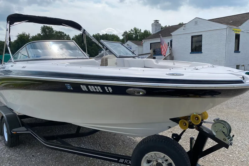 Slide: The Image of 2008 Four Winns H220 boat on trailer, parked near buildings with American flag. - 65
