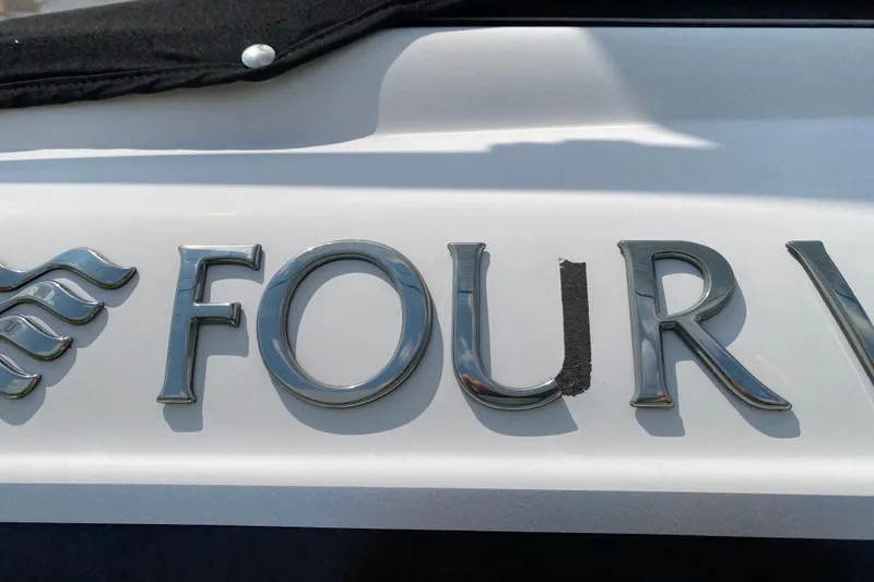 Slide: The Image of Four Winns H220 2008 boat emblem with chrome lettering on white surface. - 17