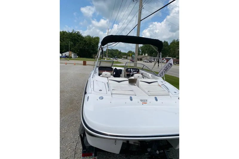 Slide: The Image of 2008 Four Winns H220 boat with white seating, parked outdoors under a cloudy sky. - 67