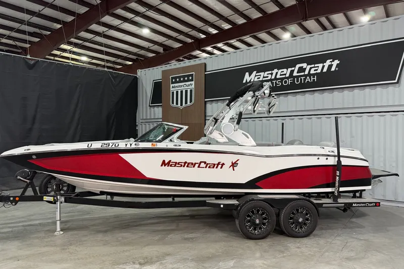 Slide: The Image of 2017 MasterCraft X46 boat in showroom, red and white design, on trailer. - 2