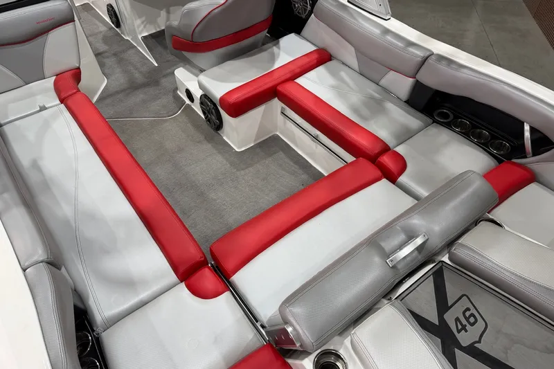 Slide: The Image of 2017 MasterCraft X46 interior with red and gray seating, cup holders, and carpeted flooring. - 7