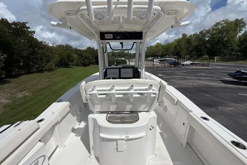 Slide: The Image of 2022 Sea Hunt Gamefish 27FS boat interior with rod holders and console, parked outdoors. - 43
