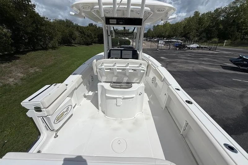 Slide: The Image of 2022 Sea Hunt Gamefish 27FS boat interior with seating and console, parked outdoors. - 37