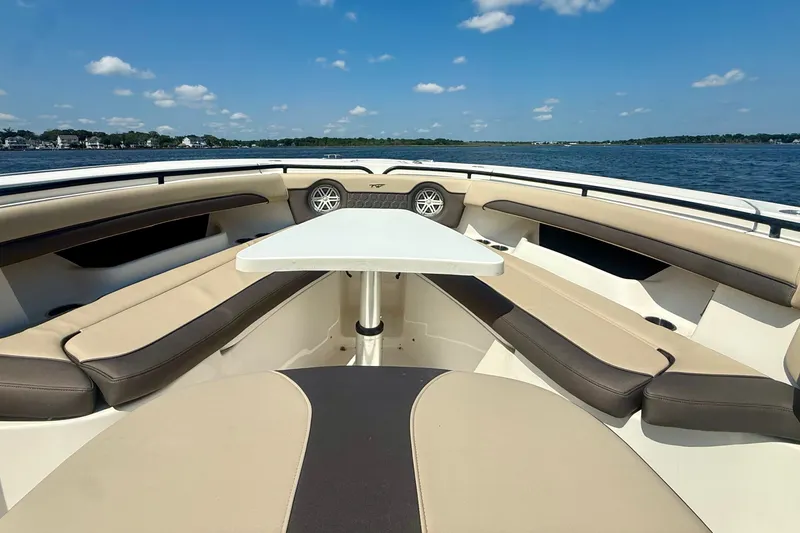 Slide: The Image of 2019 Tidewater 320 CC Adventure boat interior with seating and table on a sunny day. - 32