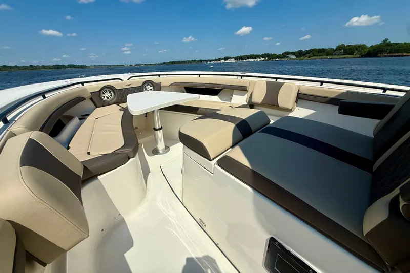 Slide: The Image of 2019 Tidewater 320 CC Adventure boat interior with cushioned seating and table on open water. - 33