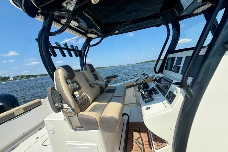 Slide: The Image of 2019 Tidewater 320 CC Adventure boat interior with helm and seating, on a sunny day. - 23