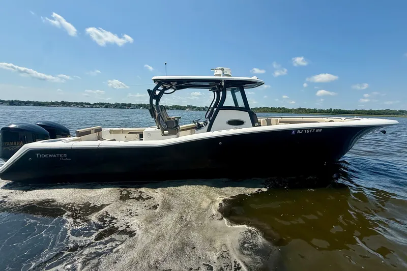 Slide: The Image of 2019 Tidewater 320 CC Adventure boat on calm water under a clear blue sky. - 2