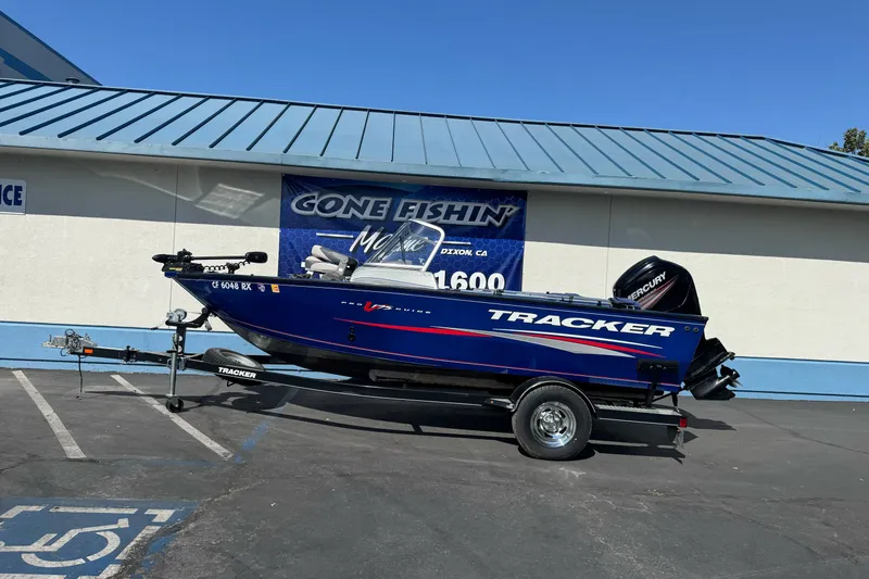 The Image of 2016 Tracker Pro Guide V-175 WT boat on trailer, parked outside a fishing store. - 1