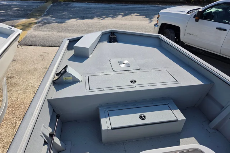 Slide: The Image of 2025 SeaArk 1872 MVT boat interior with storage compartments, parked beside a white truck. - 7