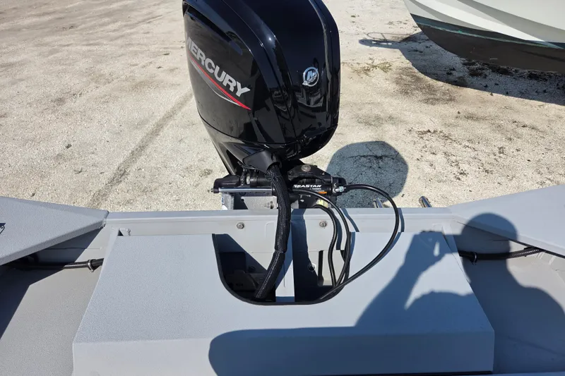 Slide: The Image of 2025 SeaArk 1872 MVT boat with Mercury outboard motor, parked on sandy ground. - 2