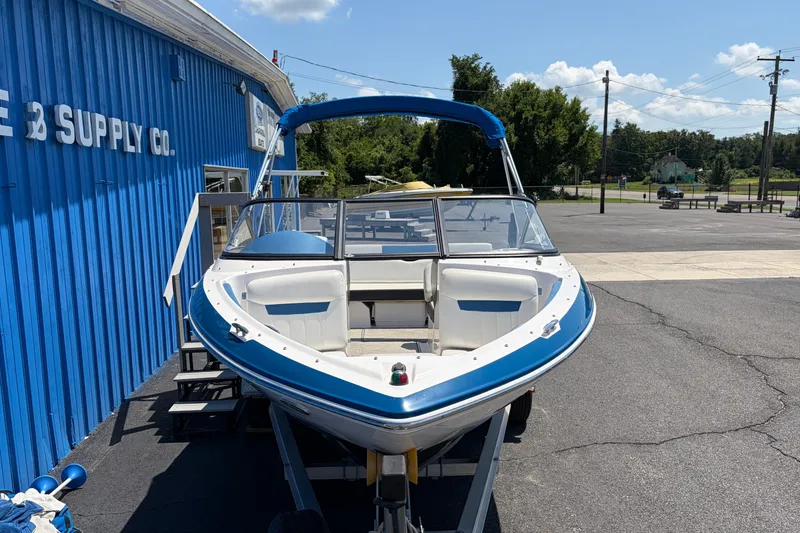Slide: The Image of 2016 Regal 1900 ESX Bowrider boat on trailer, parked outside blue building. - 3