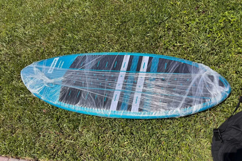Slide: The Image of A blue surfboard wrapped in plastic lies on the grass. - 56
