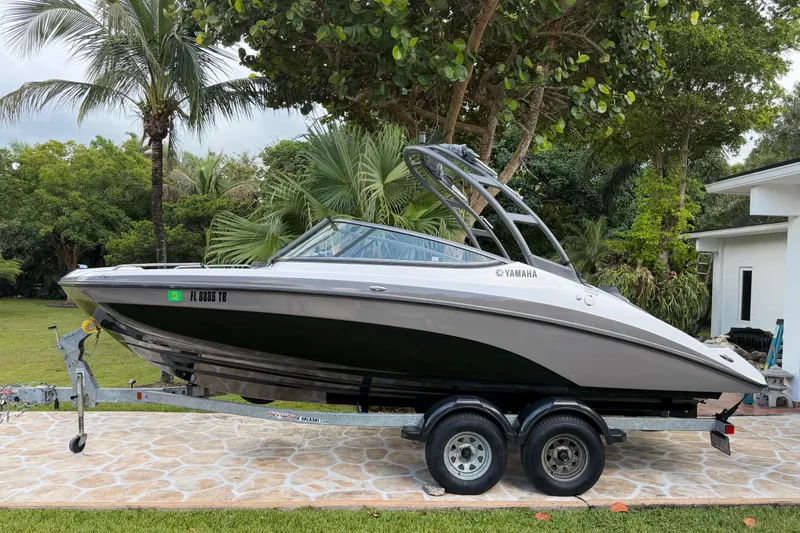 Slide: The Image of 2022 Yamaha Boats AR210 on trailer, parked outdoors with lush greenery background. - 1