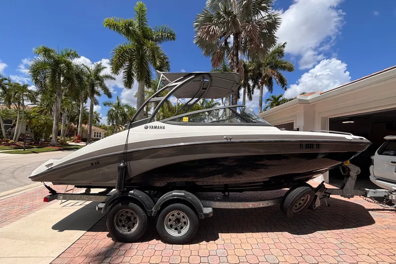 Slide: The Image of 2022 Yamaha Boats AR210 on trailer, parked in sunny driveway with palm trees. - 7