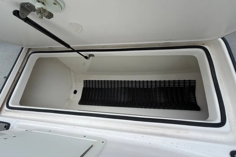 Slide: The Image of Open storage compartment in 2022 Yamaha AR210 boat, featuring a black mat inside. - 33