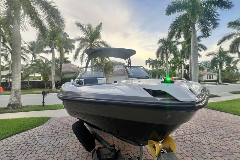 Slide: The Image of 2022 Yamaha AR210 boat on trailer, parked in a tropical residential area. - 9