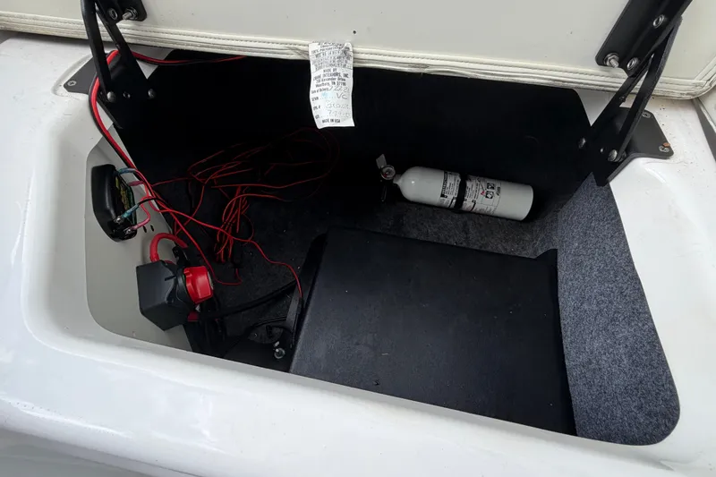 Slide: The Image of 2022 Yamaha AR210 boat storage compartment with fire extinguisher and wiring. - 13
