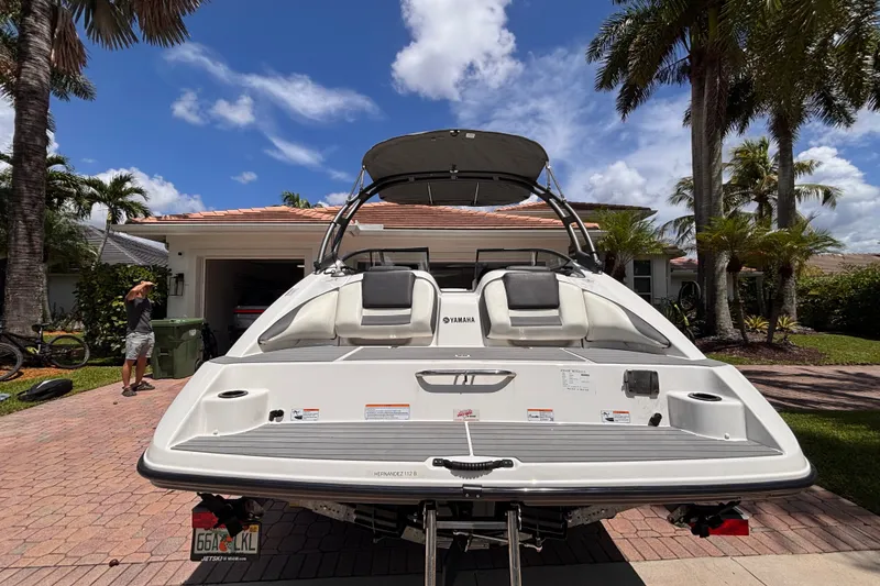 Slide: The Image of 2022 Yamaha AR210 boat parked in a driveway, surrounded by palm trees and a sunny sky. - 18