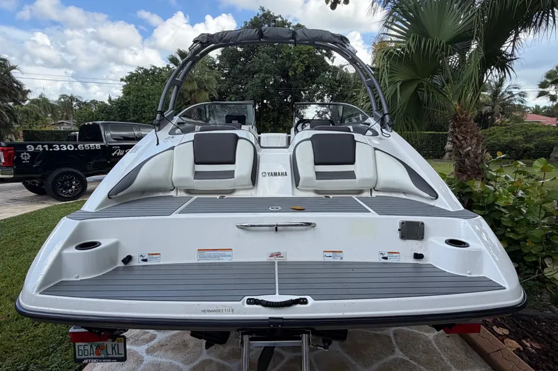 Slide: The Image of 2022 Yamaha AR210 boat with sleek design, parked outdoors, showcasing rear seating and swim platform. - 7