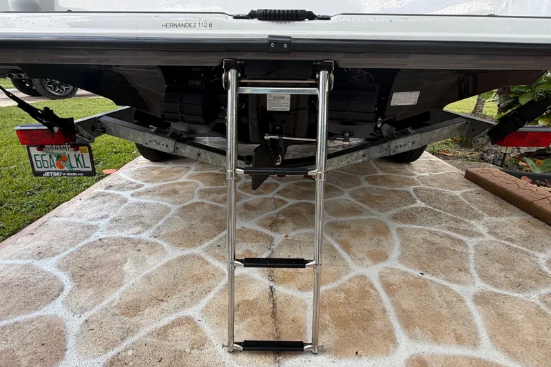 Slide: The Image of 2022 Yamaha AR210 boat with ladder on trailer, parked on patterned pavement. - 8