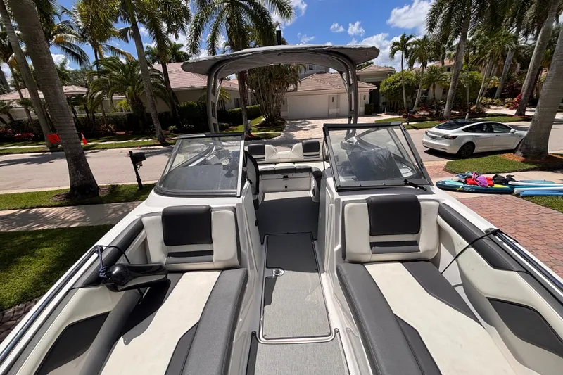 Slide: The Image of 2022 Yamaha Boats AR210 parked in a sunny residential driveway with palm trees. - 36